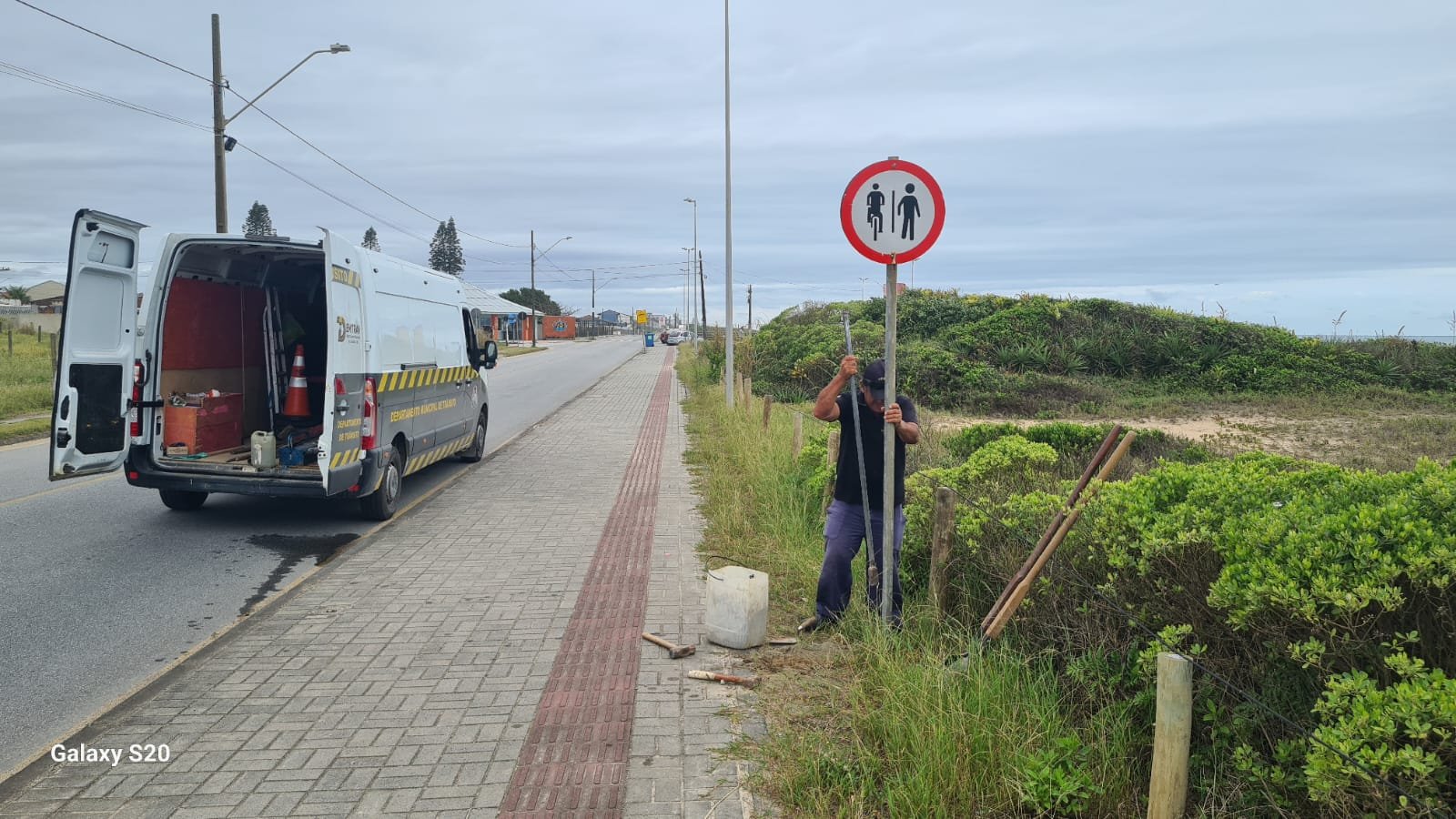 Placa de trânsito sendo reinstalada na Praia do Ervino.